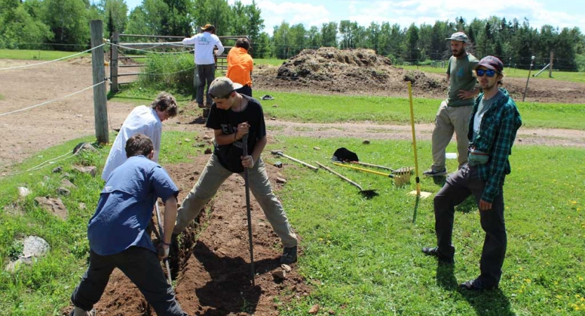 A group of young people use gardening tools during a service project with outward bound. 